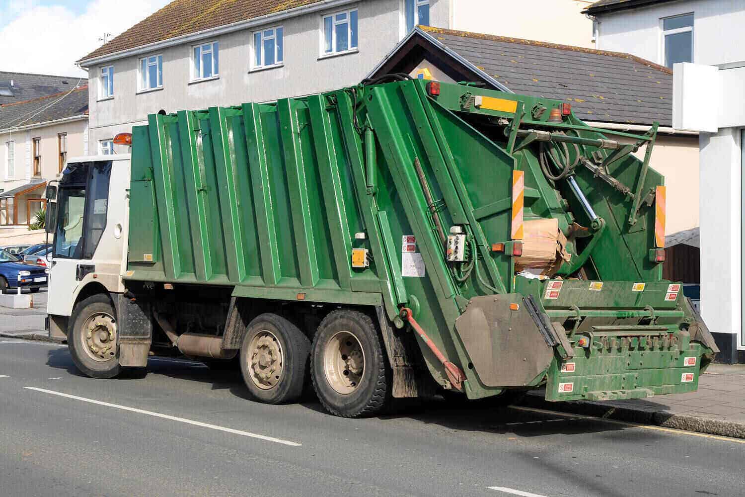 Green rubbish truck on road